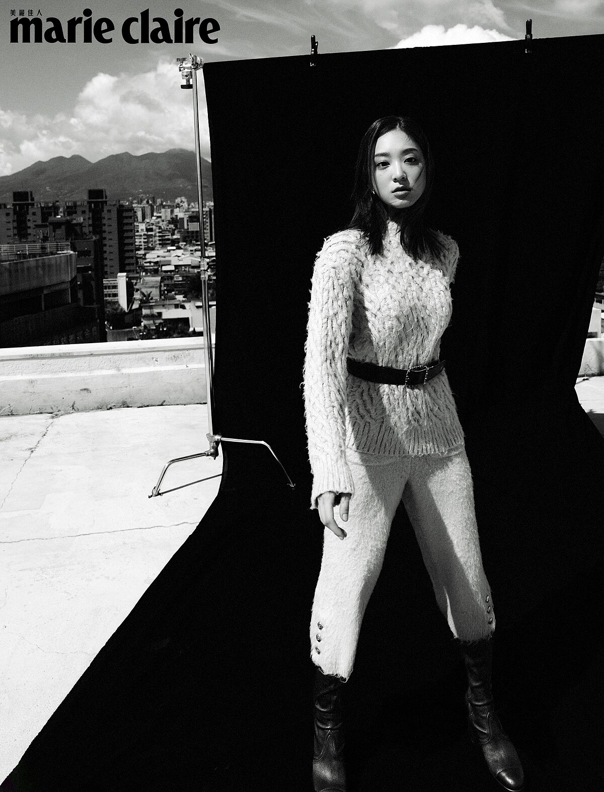 米白色毛衣、米白色短褲、酒紅色腰帶、黑色皮革長靴、金色耳環，all by CHANEL。