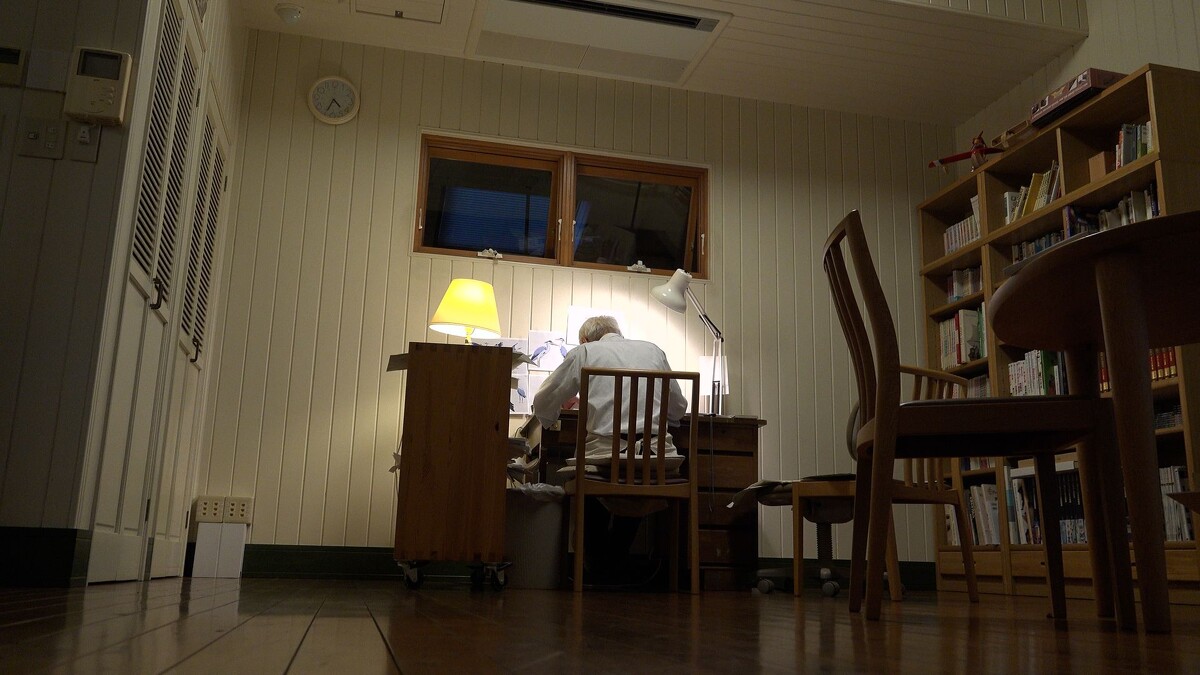 宮﨑駿在桌前伏案作畫的背影，令人聯想到《蒼鷺與少年》男主角真人