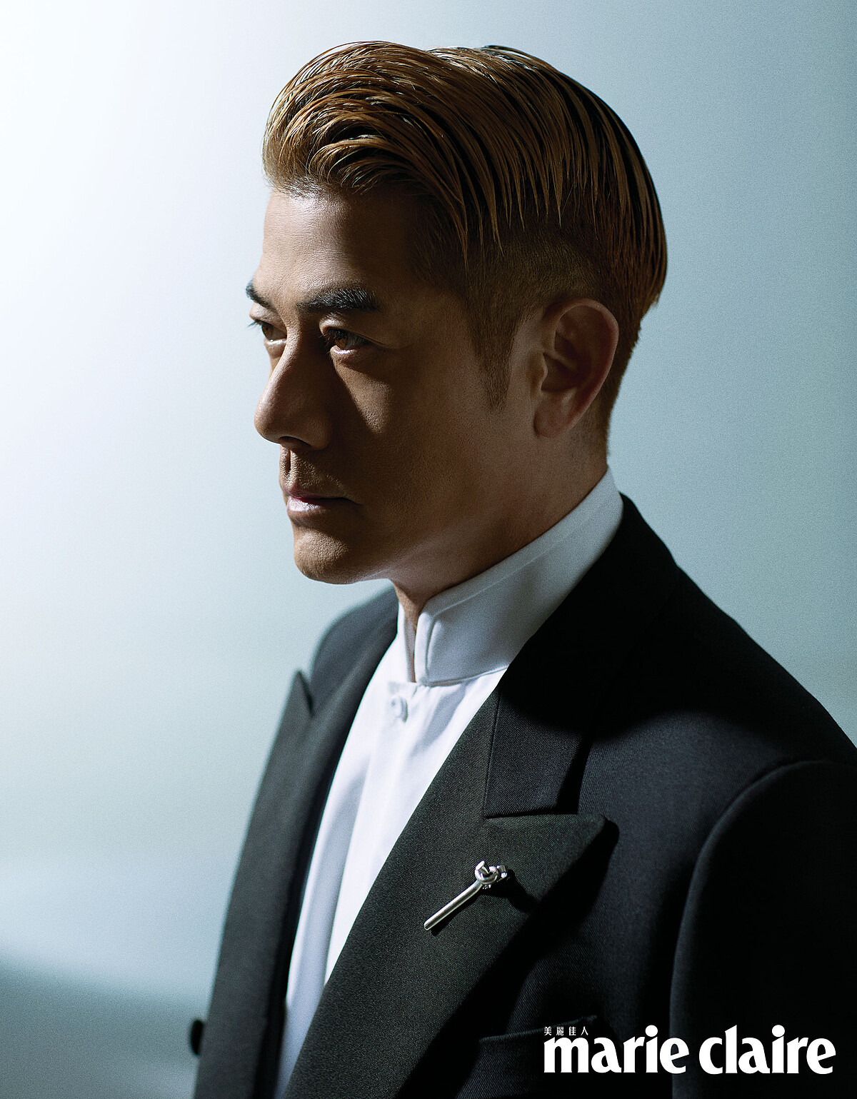 黑色羊毛和絲綢雙排扣西裝、白色棉質立領襯衫，both by Loro Piana；銀色扭結胸針、黑色皮靴，both by Bottega Veneta。