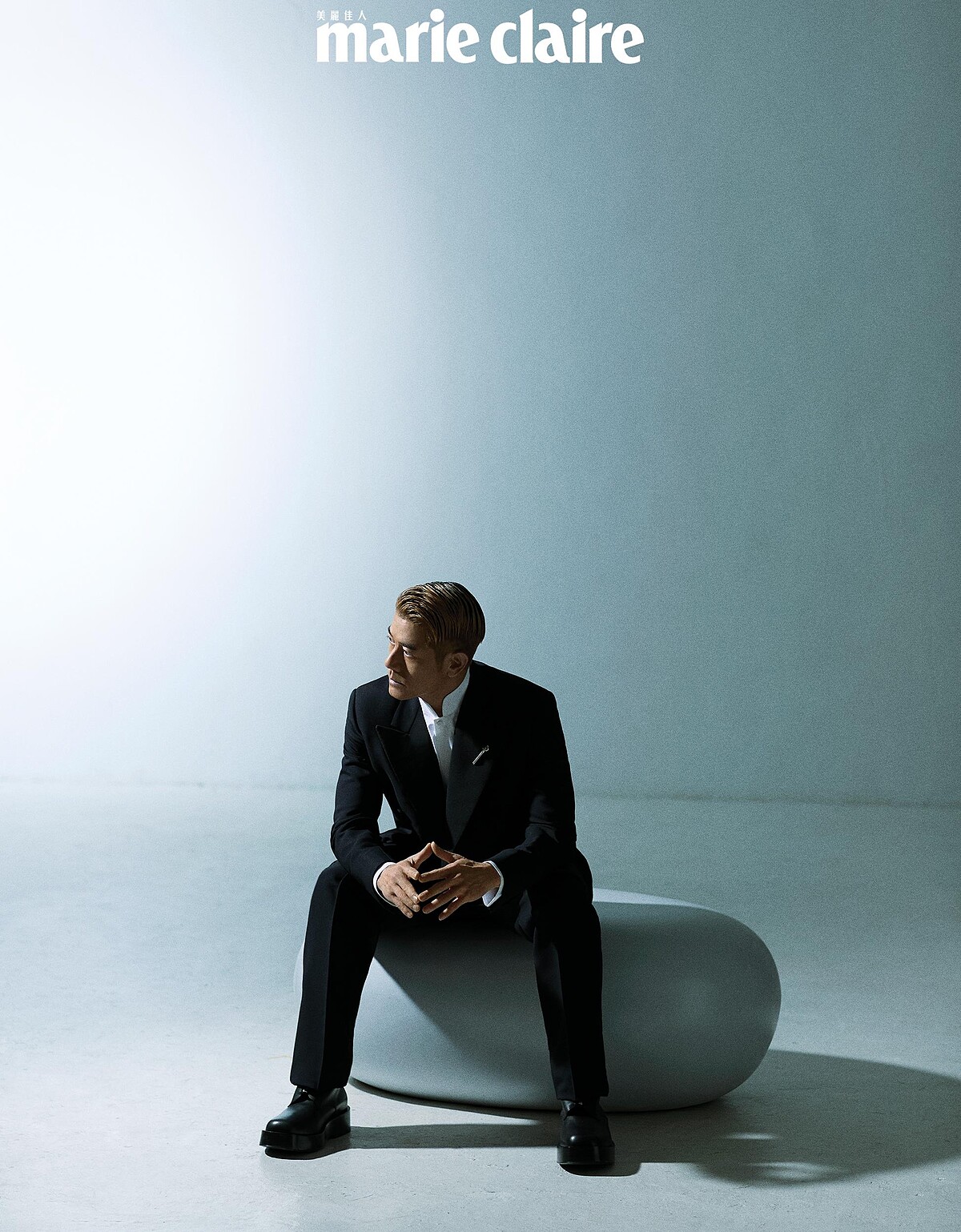 黑色羊毛和絲綢雙排扣西裝、白色棉質立領襯衫、黑色羊毛和絲綢西裝褲，all by Loro Piana；銀色扭結胸針、黑色皮靴，both by Bottega Veneta。