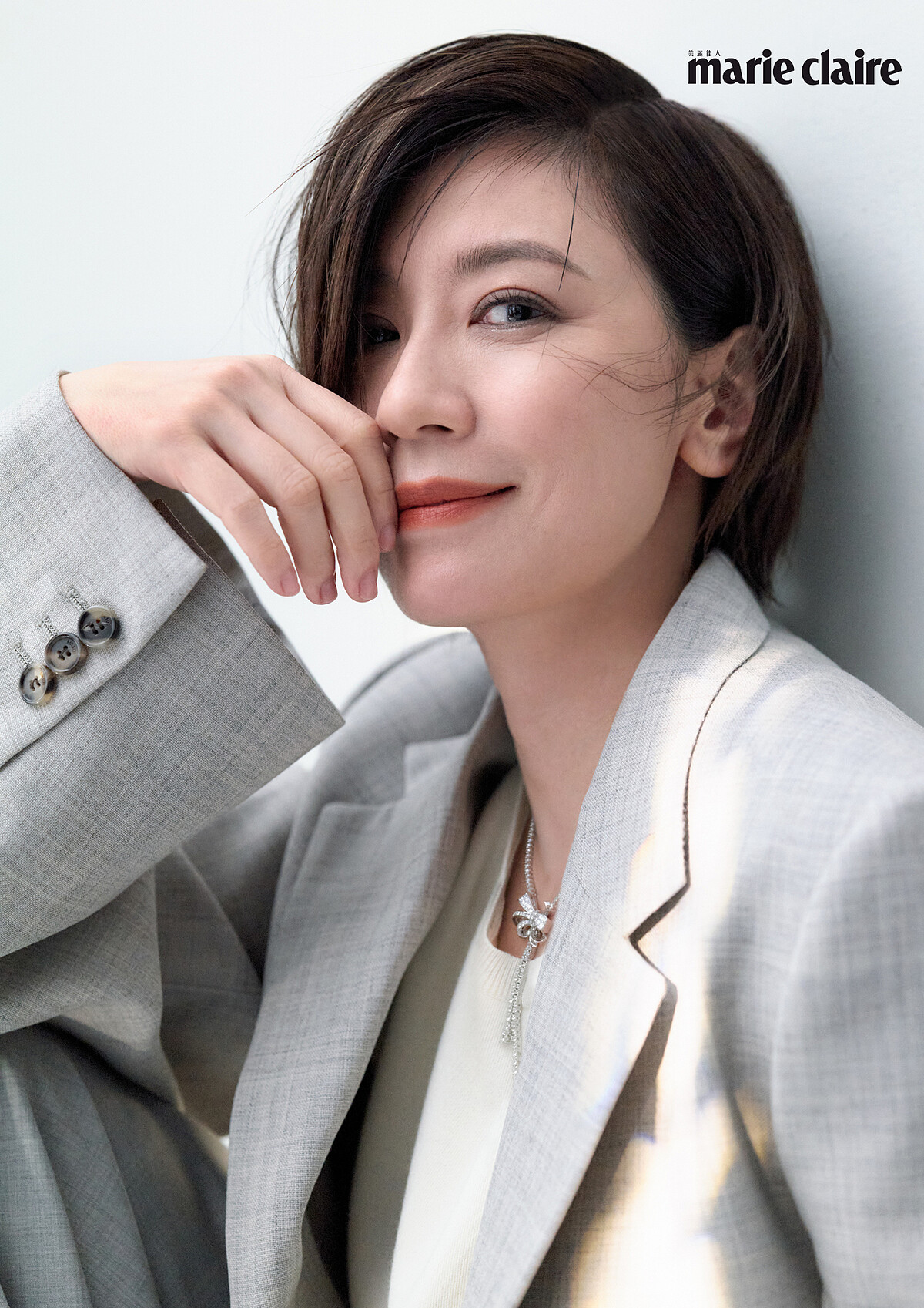 灰色西裝外套、米白針織背心、灰色寬褲,All by Loewe; Tilda's Bow系列多形切割鑽石項鏈,Graff。