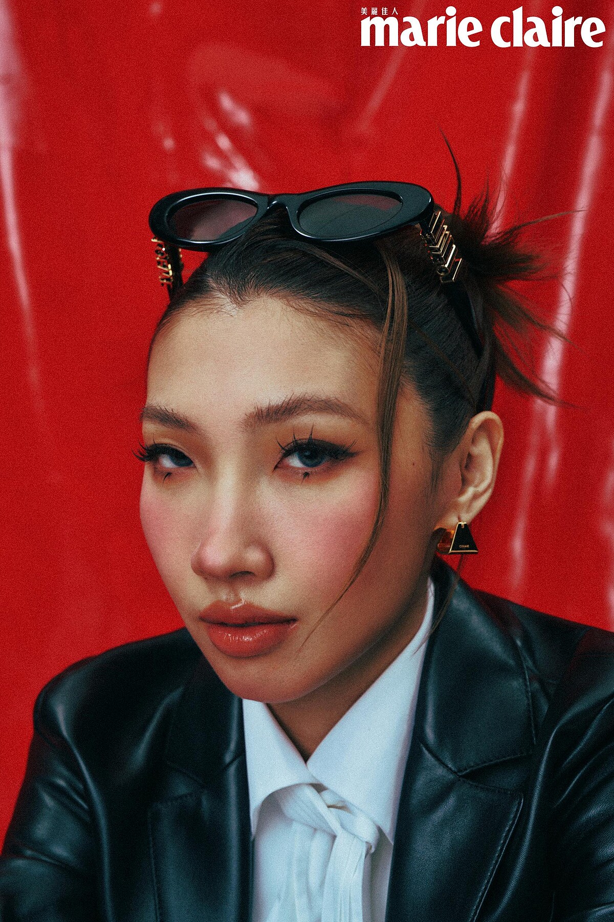  白色棉質垂墜襯衫、墨鏡，both by Loewe；黑色柔軟羊皮革西裝外套、金色飾面金字塔形圈式耳環，both by Celine by Hedi Slimane。