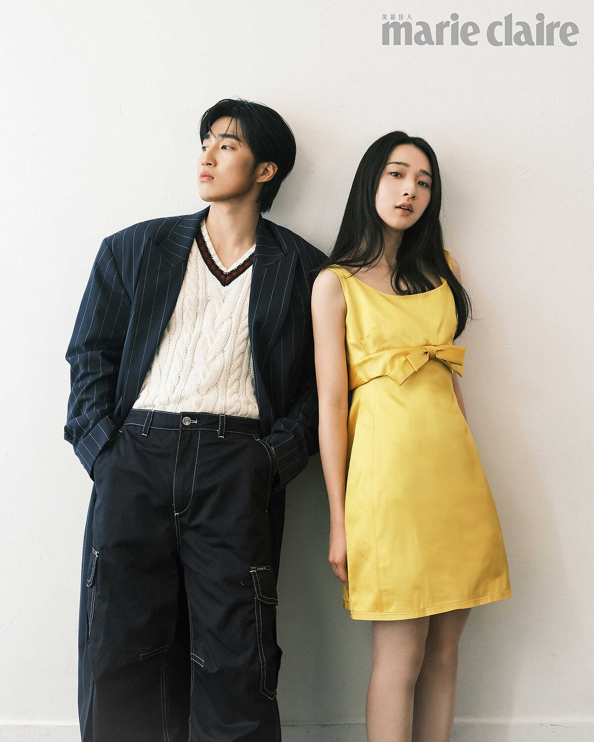 婁：深藍條紋大衣、麻花針織背心、深藍工裝褲、黑色尖頭皮鞋，all by Coach。 沐：黃色緞面洋裝，黑色瑪莉珍平底鞋，both by Coach。