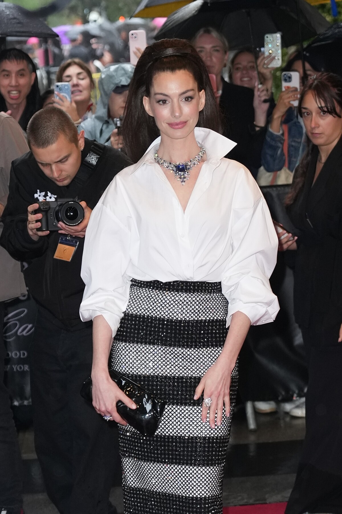 安海瑟薇 於 2025 Met Gala 紅毯，身穿 Carolina Herrera 白色開襟襯衫與刺繡條紋窄裙