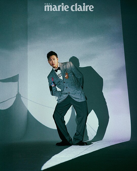 煙灰色工裝直條紋西裝外套、白色 Logo 標語襯衫、煙灰色工裝直條紋西裝褲，All by Moschino；彩色星星領結、黑色皮鞋，Both by Paul Smith。