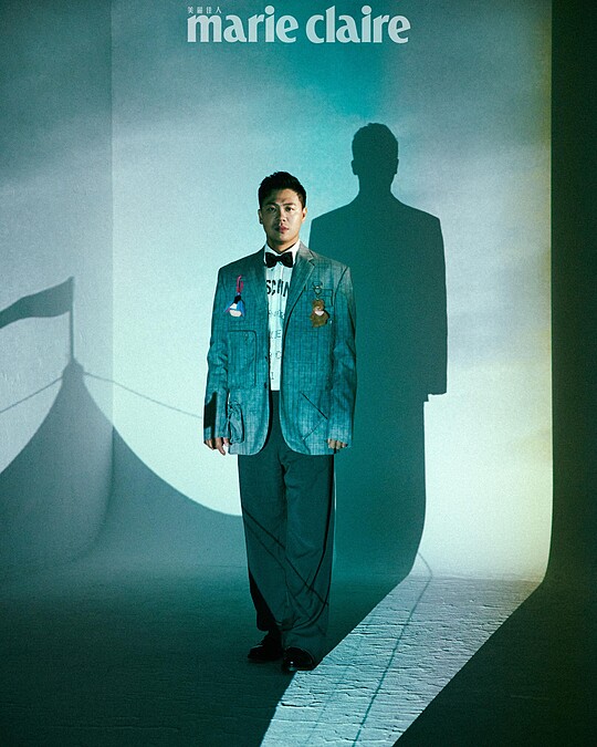 煙灰色工裝直條紋西裝外套、白色 Logo 標語襯衫、煙灰色工裝直條紋西裝褲，All by Moschino；彩色星星領結、黑色皮鞋，Both by Paul Smith。