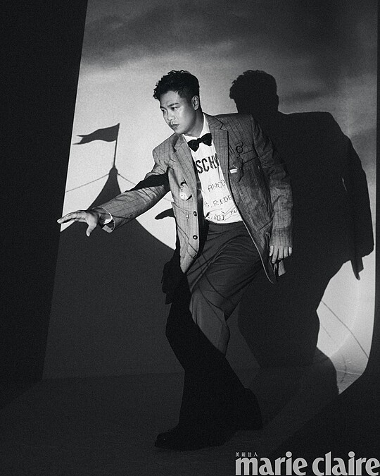 煙灰色工裝直條紋西裝外套、白色 Logo 標語襯衫、煙灰色工裝直條紋西裝褲，All by Moschino；彩色星星領結、黑色皮鞋，Both by Paul Smith。