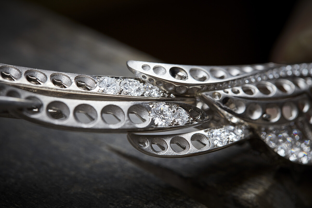 將部分完成鑲嵌的羽毛組裝於 EMBRACE YOUR DESTINY 項鍊的左翼上。