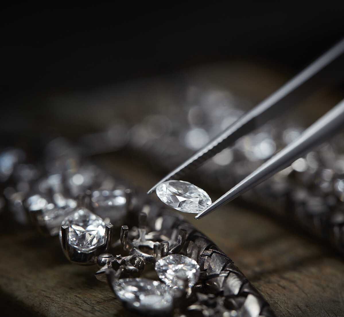 將一顆花式橢圓形切割寶石安置於 DREAMS COME TRUE 項鍊上，​確認與其他寶石的相對高度。