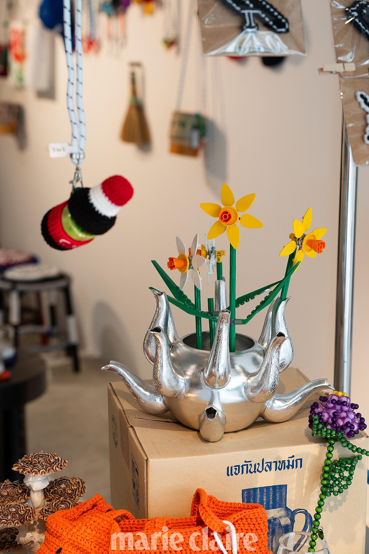 擅長用熟悉的材料去探索工藝的新型態。舉例像是這個可口可樂「Ya Dom」盒，就是由在地工匠手工編織而成，靈感來自泰國傳統的清涼油吸嗅器。旁邊的鬱金香花瓶則是用經典的泰式鋁製 Ketal 做成的，有趣可愛。