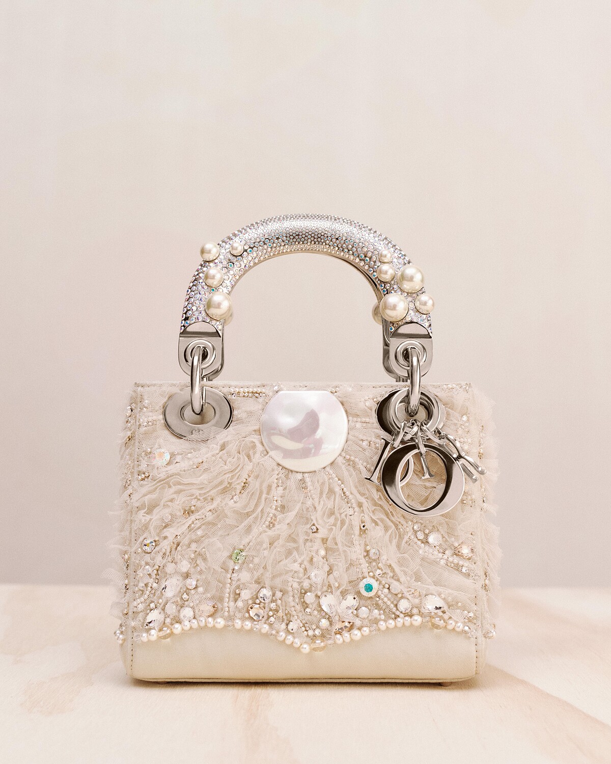 Dior Lady Art Jessica Cannon 迷你提包，以米色緞面製成，包身綴以薄紗、珍珠與施華洛世奇水鑽刺繡。包款提把採用銀色金屬製作，鑲嵌滿滿水晶與珍珠，金屬飾件為銀色金屬材質。&copy; Joe Perri