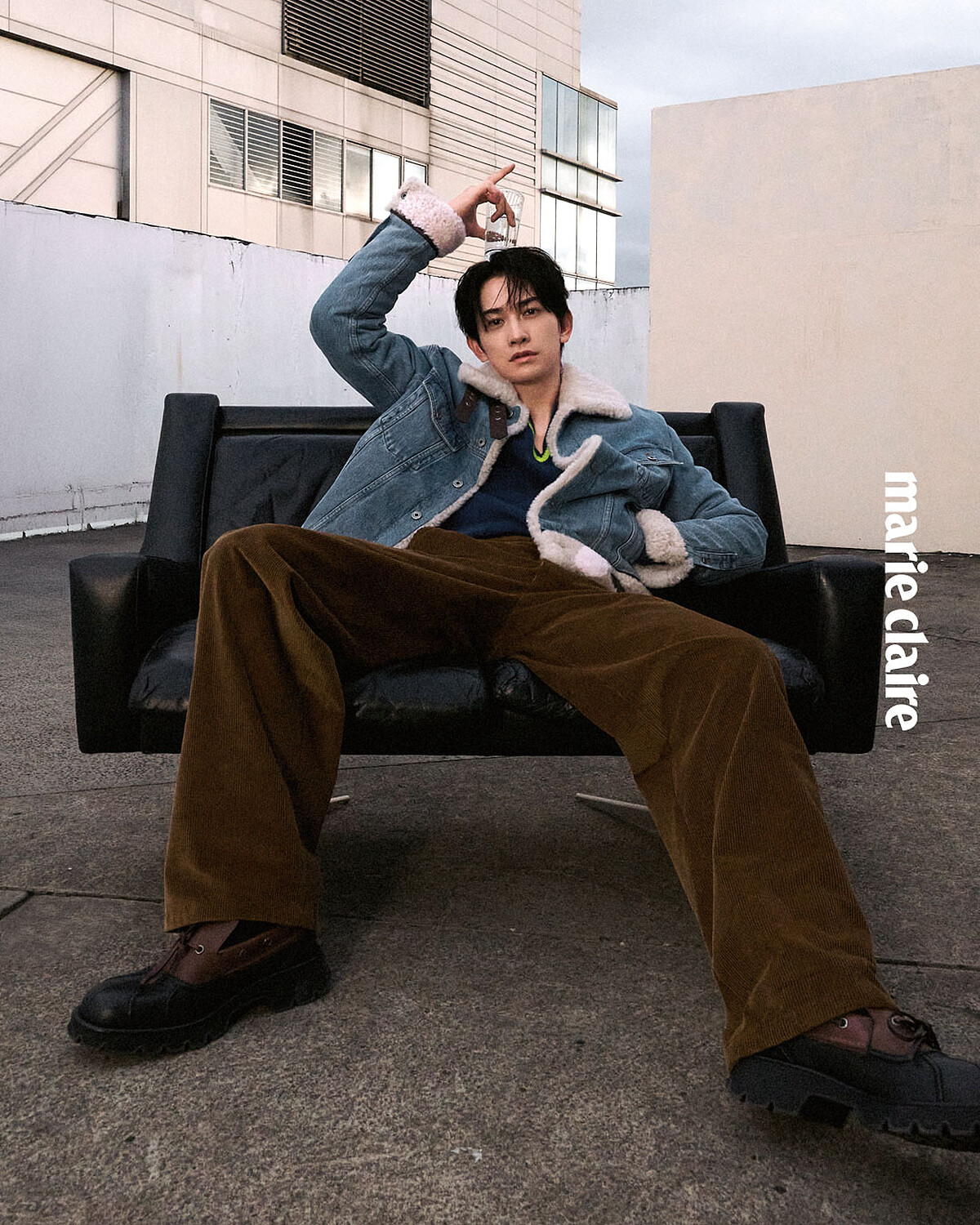 丹寧卡車司機外套、黃藍色V領針織衫、棕色長褲、小牛皮撞色德比鞋，All by Loewe。