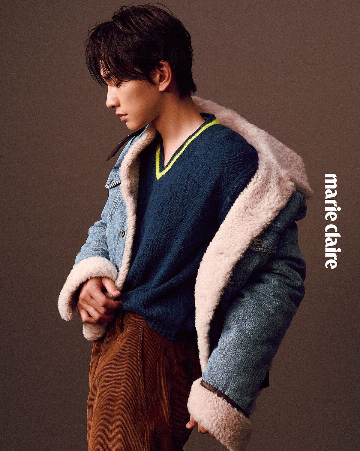 丹寧卡車司機外套、黃藍色V領針織衫、棕色長褲、小牛皮撞色德比鞋，All by Loewe。