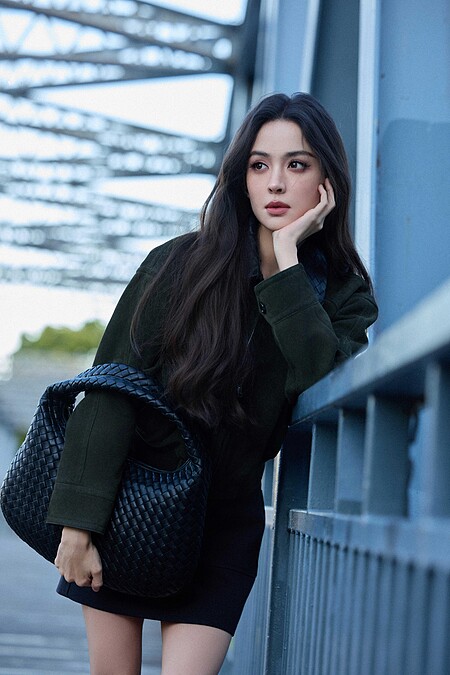 古力娜扎身穿一件深綠色麂皮襯衫搭配黑色迷你短裙，並手拿一顆Bottega Veneta 黑色Veneta包款，展現都會時髦的簡約俐落樣貌。
