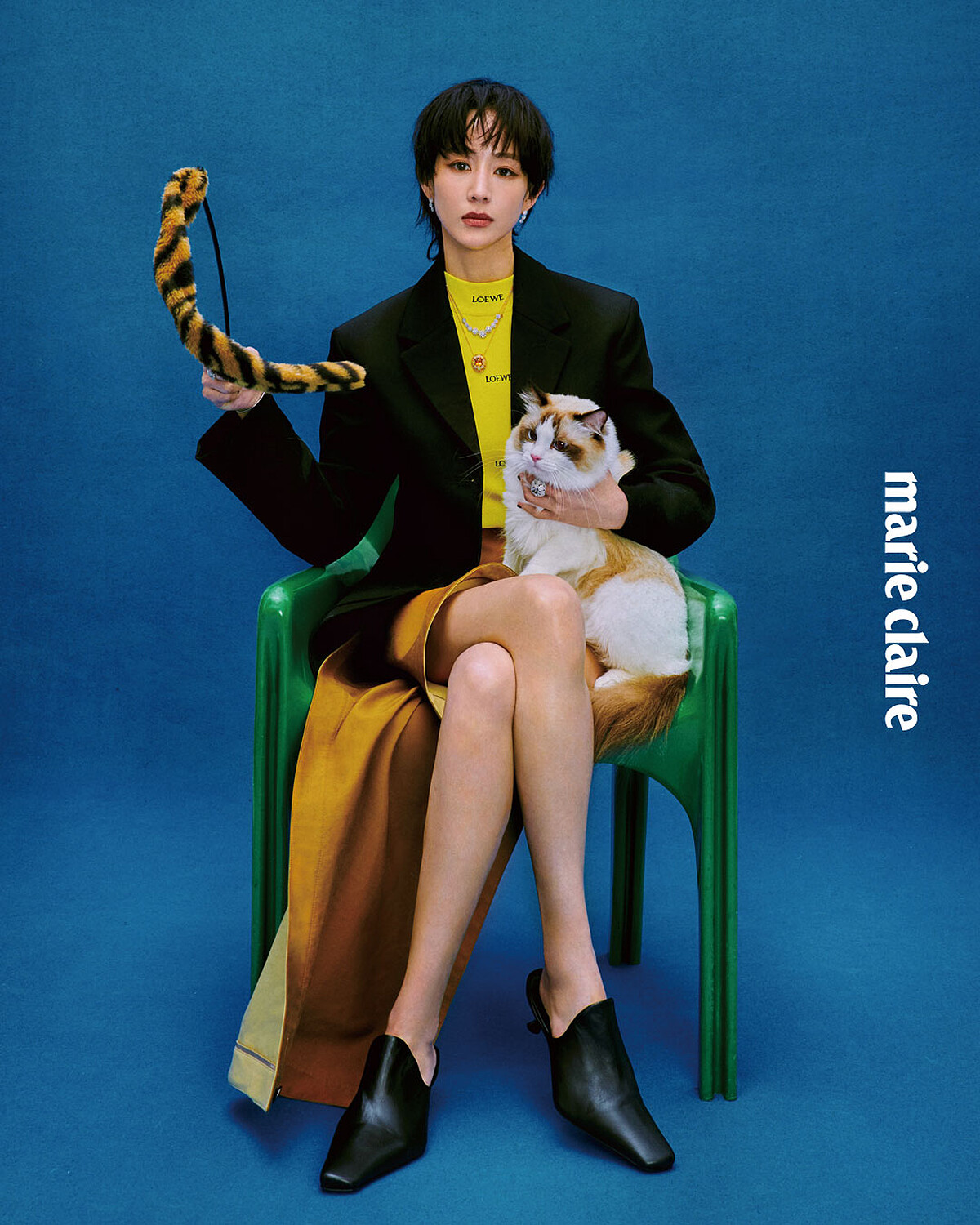 黑色西裝外套、半高領黃色上衣、駝色不對稱裙，all by Loewe； Margherita 瑪格麗特系列18K 黃金黃水晶與鑽石項鍊、Margherita 瑪格麗特系列18K 白金鑽石九朵花卉項鍊、Margherita 瑪格麗特系列18K白金鑽石花卉手環、Margherita 瑪格麗特系列18K 白金鑽石花卉耳環、兩只 Margherita 瑪格麗特系列18K 白金鑽石花卉戒指，Margherita 瑪格麗特系列18K 白金海水藍寶石與鑽石戒指，all by DAMIANI。