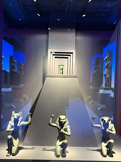 這三尊塑像可能用來裝飾遊行時運載神像的聖船，中間是一位國王，左右為豺狼首的「尼肯之荷魯斯」與隼首「佩之荷魯斯」，象徵統一前上下埃及古都靈魂，在法老加冕與慶典時守護君王。Melody TU 採訪拍攝