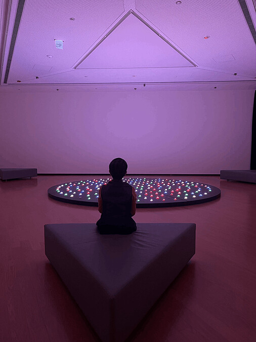 〈十界互具〉燈光閃爍的數字象徵眾生輪轉的生滅。圓形展台位在美術館正中央，與正三角形的建築有幾何上的對應。