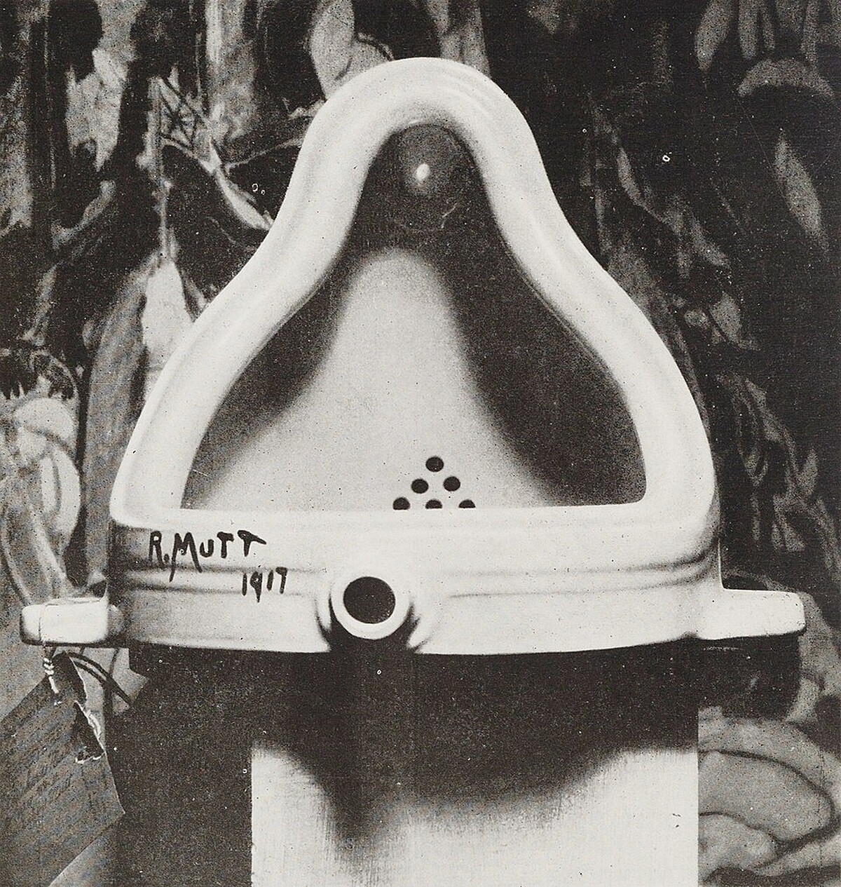 1917年時，由阿爾佛雷德&middot;斯蒂格利茲（英語：Alfred Stieglitz）為《噴泉》拍攝的照片，後方則為美國畫家馬森&middot;哈特利（英語：Marsden Hartley）的作品《戰士們》（The Warriors）｜圖片來源：wikipedia