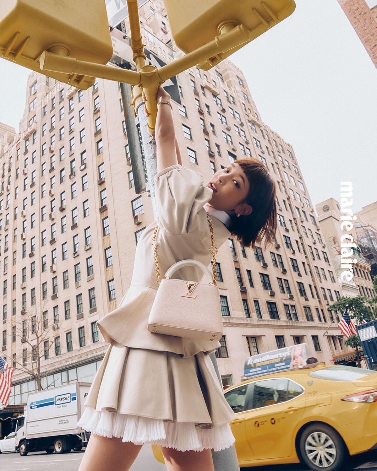 白色短身蝴蝶結襯衫、泡泡袖外套、荷葉邊迷你短裙、Le Damier de Louis Vuitton 耳環,黃K金、鑽石,Capucines BB包,all by Louis Vuitton。